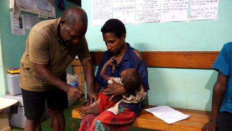Paul Isilawa giving an injection to an infant at Mougulu health centre
