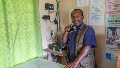A man holds a radio mouthpiece and smiles