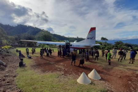 a crowd around the plane as the patient gets loaded at Pyarulama