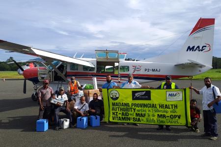 a team from the Madang Provincial Health Authority posing with a banner to say thank you to MAF and NewZealand Aid for their support for the Measles-Rubella Supplementary Immunization Activity (MRSIA) campaign