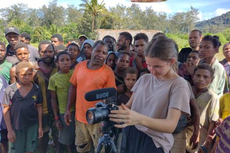 Ashley Leyenhorst video interviewing with a crowd of people behind her