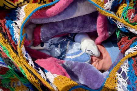 a newborn baby snuggled up in a bilum 