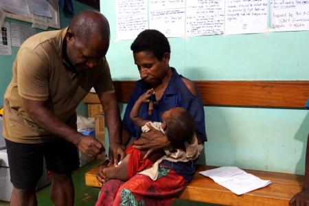 Paul Isilawa giving an injection to an infant at Mougulu health centre