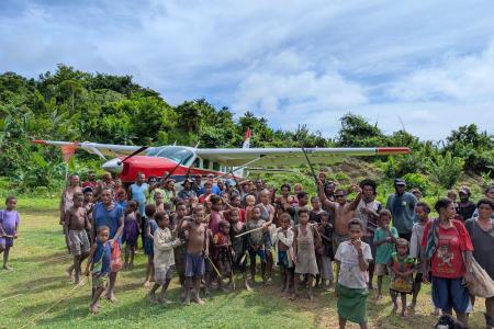 P2-AHP after its first landing at Moka airstrip with people joyfully gathered around the plane