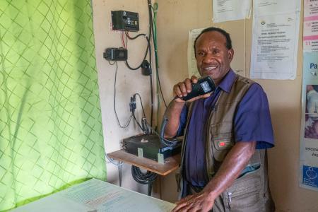 A man holds a radio mouthpiece and smiles