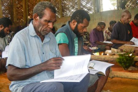 A man sits and reads the Bible and a workbook