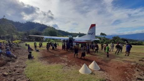 a crowd around the plane as the patient gets loaded at Pyarulama