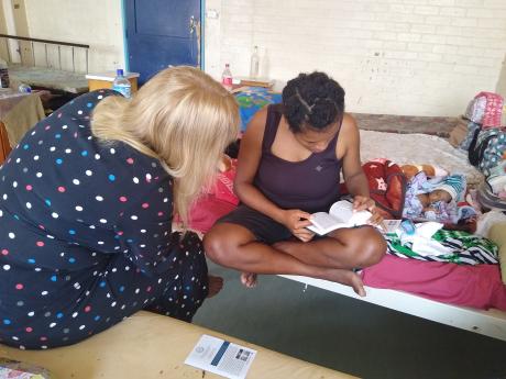 A Mama Care Ministry volunteer sharing a Tok Pisin Bible with one of the mothers.