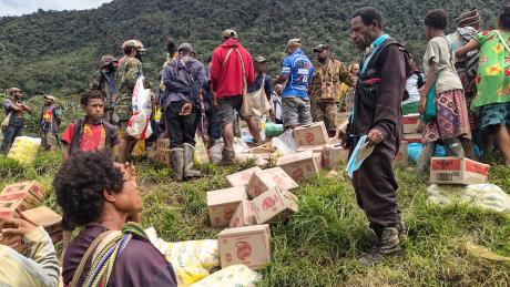 A group of teachers and health workers sort through supplies on the side of an airstrip