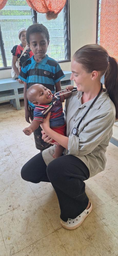 Sara holding an infant with Loni standing in the background