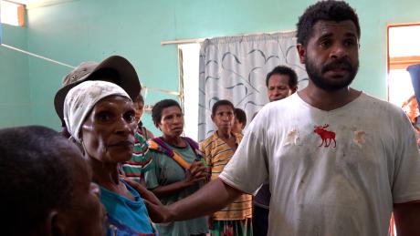 Titus Yabua standing with women in the Mougulu health post