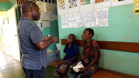 Paul Isilawa talking to a mum and her child about the correct medication