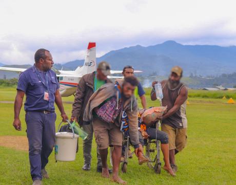 Mary in a wheelchair alongside her husband John, their son, and the MAF Goroka team.