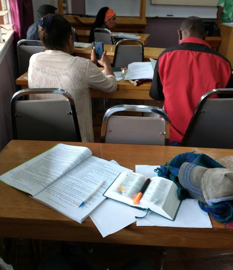 A picture displaying an open Bible and a course book on a table.