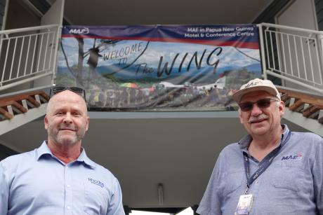 Brian Kenny and Dave Moore pose in front of 'The Wing' banner