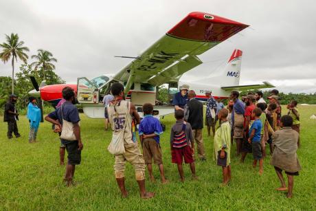 Jamie Gudego talking to Dan Shaw at Honinabi in front of the MAF aircraft and surrounded by other people from the community