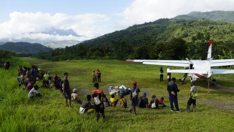 MAF plane at Sisamin with people around the airstrip /parking bay perimeter 