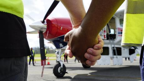 MAF's new Cessna Caravan P2-AFD arriving in PNG and surrounded by MAF staff in a prayer circle