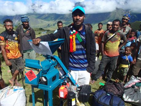 Helson standing next to the rice mill delivered to Ambi