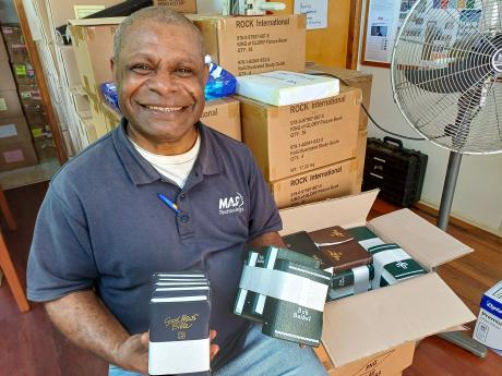 A man smiling holding Bibles