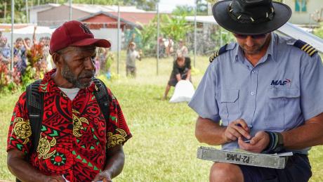 A man helps a pilot with pre-flight paperwork